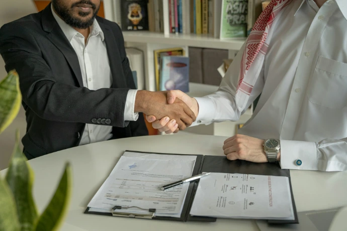 a couple of men shaking hands over a desk